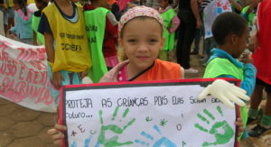 Ein Mädchen hält während einer Demonstration ein selbst gemaltes Plakat mit portugiesischer Aufschrift hoch. (Quelle: Stefanie Feuersinger)