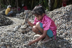 Ein Mädchen zerklopft Steine. (Quelle: Christian Herrmanny)