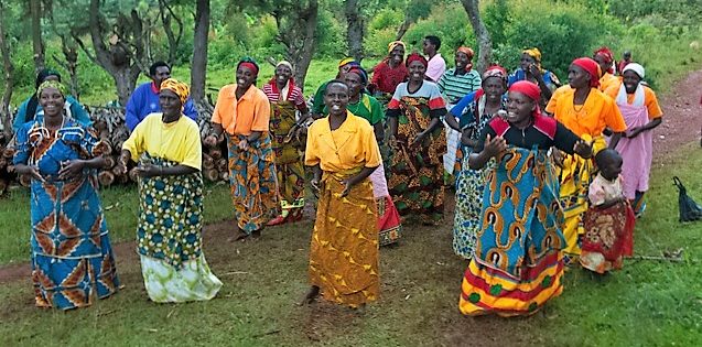 Ruandische Frauen in bunter Kleidung tanzen auf einer Wiese. Quelle: Dietmar Roller