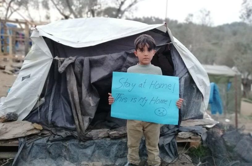 Ein Junge steht mit einem Pappschild vor einem Zelt (Quelle: MCAT Muhannad Al-Mandeel)